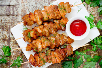 Grilled meat skewers shish kebab on plate with tomato sauce