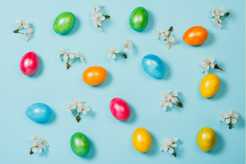 Easter eggs and spring flowers on a blue background. Concept of celebrating Easter. Flat lay, top view