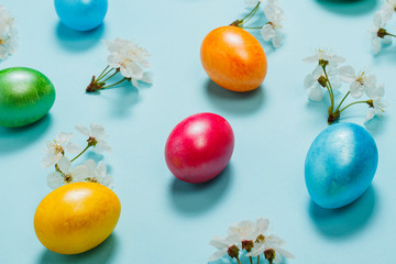 Easter eggs and spring flowers on a blue background. Concept of celebrating Easter. Flat lay, top view