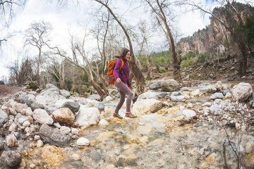 Woman jumps over the mountain river.