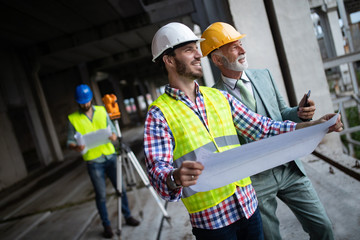 Team of architects and engineer in group on construciton site check documents and business workflow