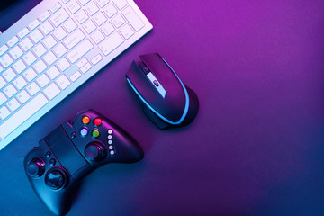 Keyboard, mouse and joystick on violet table background.