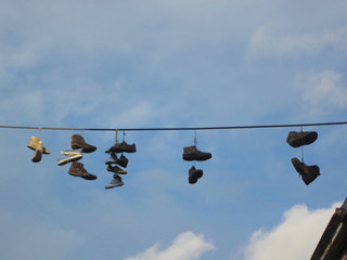 seven pair of shoes hanging on an electricity cable above the street