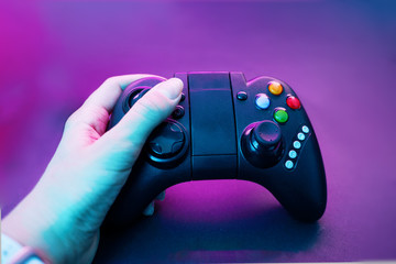 Hand with gamepad on violet table background.