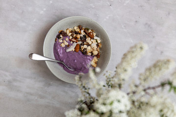 Bowl of granola with yogurt and nuts on marble background