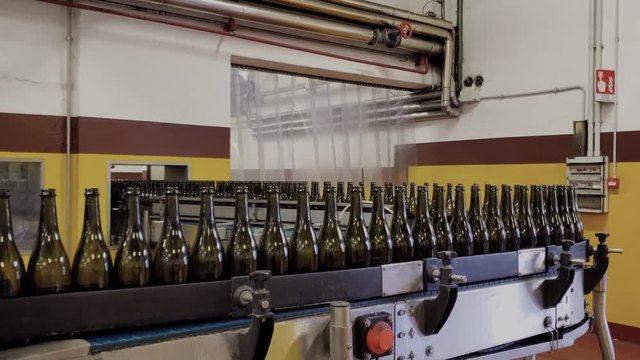 An industrial conveyor belt transporting thousands of empty wine bottles to be cleaned and filled in a production facility
