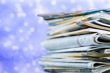 Pile of newspapers on blurred background, close up