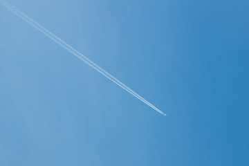 Trail of jet plane on clear blue sky.