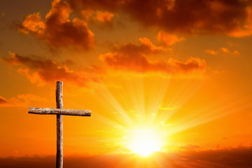 close up wooden cross over orange colored sunset sky