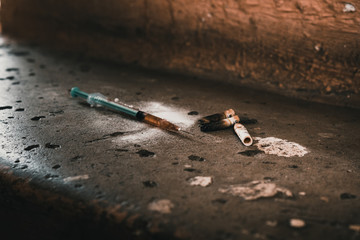 Heroin syringe on rough concrete, dirty background