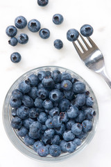 Blueberries on a glass dish with a fork.
