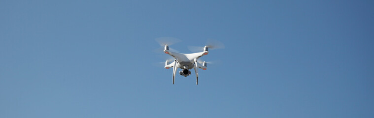 Drone on blue sky background. Remote control quadrocopter with camera for photography. Flying robot.