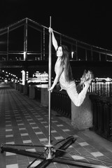 Monochrome Slim, fit, athletic beautiful redhead woman on pylon on Pedestrian bridge (Kyev, Ukraine) background at night