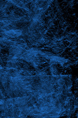 Transparent blue plastic wrap on the black background. Plastic shopping bag texture. Reusable trash and waste.