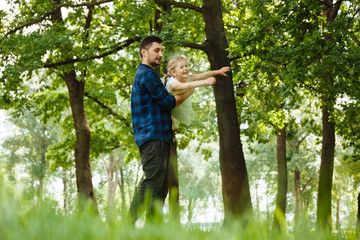 Dad and daughter have fun in park, girl flies with her father in his arms. Happy childhood.