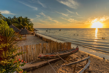 The beach of Ifaty, Mangily, near Toliara / Tulear South West Madagascar. Tropical sandy beach, thatched huts, exotic vegetation, traditional wooden fishing boat, people swimming and beautiful sky