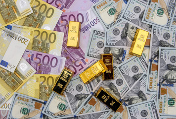 Golden ingot on american dollars and euro banknotes