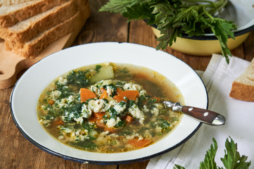 Nettle soup with vegetables and eggs in a white bowl