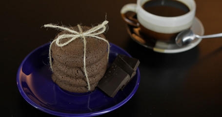 Tasty looking chocolate cookie on a blue plate on dark surface