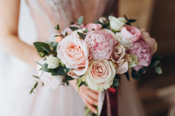 Obraz na płótnie Canvas Brides wedding bouquet with peonies, freesia and other flowers in women's hands. Light and lilac spring color. Morning in room