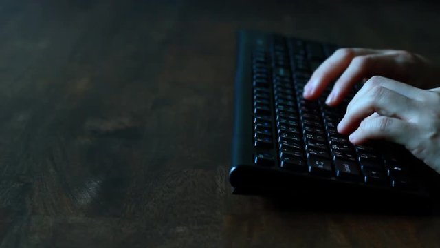Woman female developer is typing programming software script source code on keyboard on dark wood table  (side view). For SDLC, hi tech background or intro clip