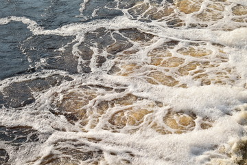 Dark water flowing with white foam