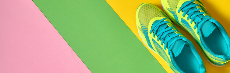 Pair of sport running shoes on colorful background. New sneakers on green, yellow and pink...