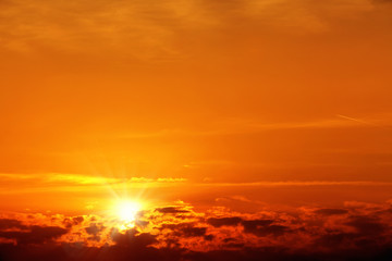 Naklejka na ściany i meble Beautiful cloudscape of orange colored sunset sky with shining sun