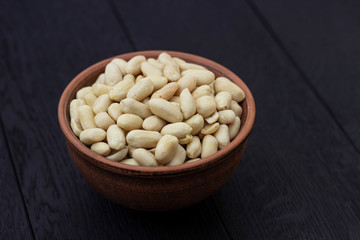 peanuts in ceramic bowl on oak table