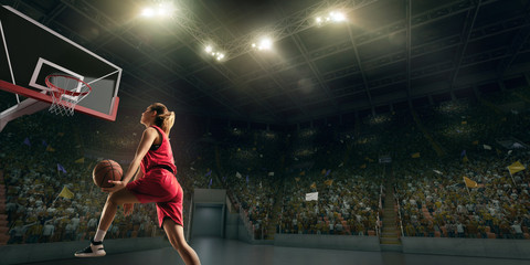 Female basketball player makes slam dunk. Basketball player on big professional arena during the...