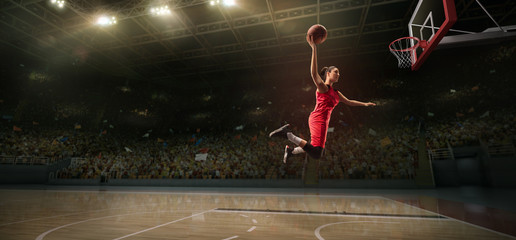 Female basketball player makes slam dunk. Basketball player on big professional arena during the game © Alex