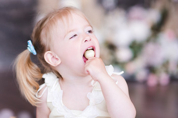 Funny baby girl 1-2 year old eating lollipop closeup. Childhood.