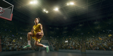 Female basketball player makes slam dunk. Basketball player on big professional arena during the...
