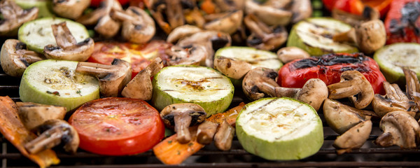 Healthy food preparing outdoors on summer or spring picnic. Grilled vegetables on grill on coals. Barbecue picnic on a meadow