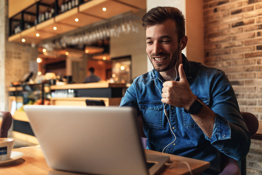 Young man sitting at cafe and making video call on laptop.