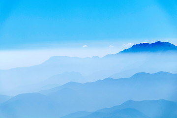 Abstract cascade mountain chains silhouette landscape nackground in a light blue mist sky in morning Andes