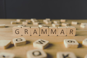 selective focus of word grammar made of cubes surrounded by blocks with letters on wooden surface...