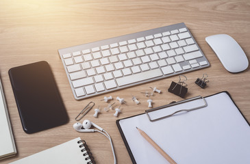 Workspace with diary or notebook and clipboard, mouse computer, keyboard, smart phone, Earphone, pencil, pen on wooden background
