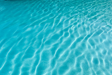 Fototapeta na wymiar Surface of rippled blue swimming pool
