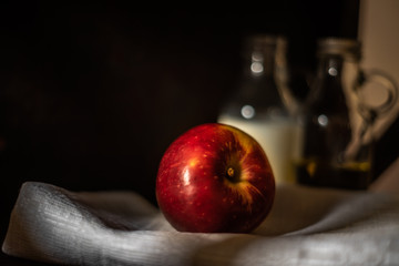 Fresh red apple on linen fabric with blurred glass bottles background