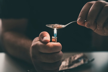 Addict at the table with a syringe heroin methamphetamine addiction - obrazy, fototapety, plakaty
