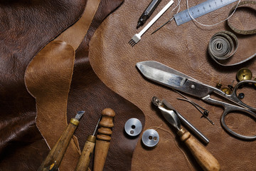 Pieces of natural cow leather and working tools in the tailoring workshop. Top view.