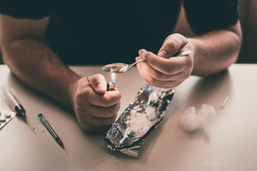 Addict at the table with a syringe heroin methamphetamine addiction - obrazy, fototapety, plakaty