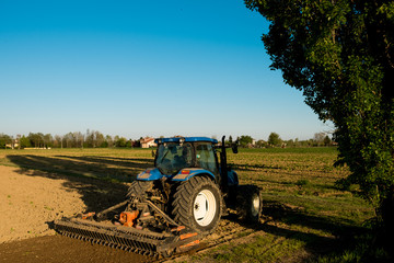 heavy truck plow up corn field in the italian countryside of veneto at sunset on summer day, symbol...