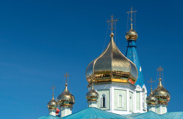Fototapeta na wymiar Golden domes of the Russian Orthodox Church against the blue sky