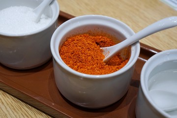 Selective focus of cayenne pepper is seasoning container set for noodle on wooden table in restaurant, Thai food style, Soft focus