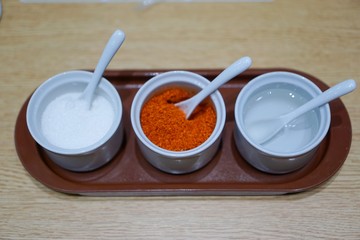 Seasoning container set for noodle to consist of cayenne pepper, sugar and vinegar on wooden table in restaurant, Thai food style, selective focus