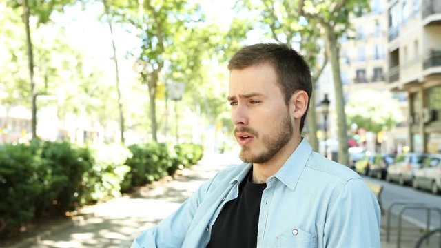 Portrait of an asmathic man using asthma inhaler relieving symptoms in the street