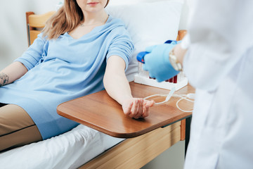 partial view of doctor preparing donor for blood donation in clinic