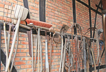 alte Hacke besen forke halfter schippe spaten an der wand beim bauern